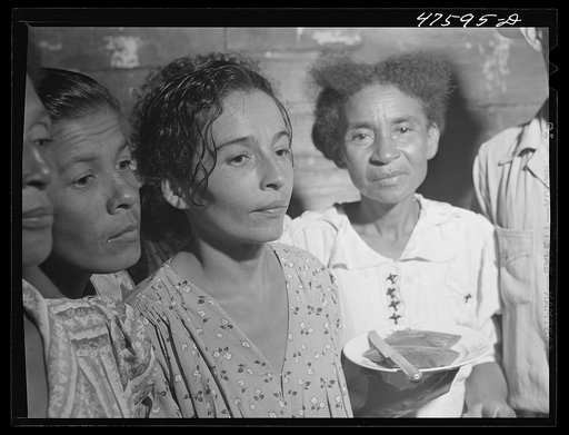 Guanica, Puerto Rico (vicinity). At a Three Kings' eve party in the home of a farm laborer's family. The woman is serving "pastellas" [i.e. pasteles], a tamale-like dish made with plantain