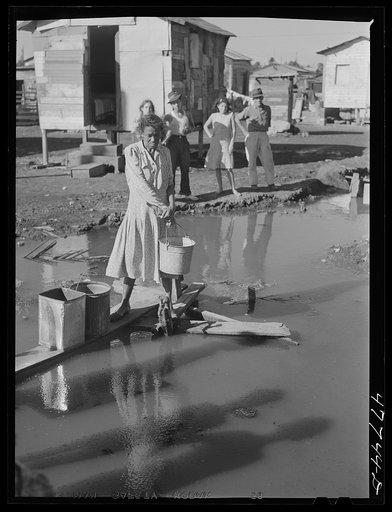 Untitled photo, possibly related to: San Juan, Puerto Rico. Fetching water from a spigot which services many people who live in the huge slum area known as "El Fangitto" ("the mud")