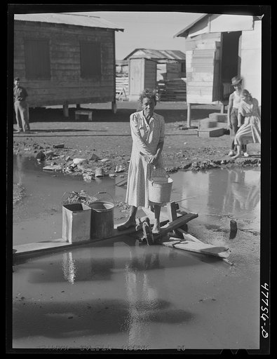 San Juan, Puerto Rico. Fetching water from a spigot which services people who live in the huge slum area known as "El Fangitto"