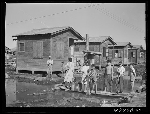 San Juan, Puerto Rico. Fetching water from a spigot which services many people who live in the huge slum area known as "El Fangitto" ("the mud")