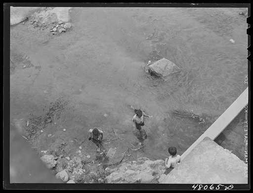 San Sebastian, Puerto Rico (vicinity). Children playing in a contaminated river