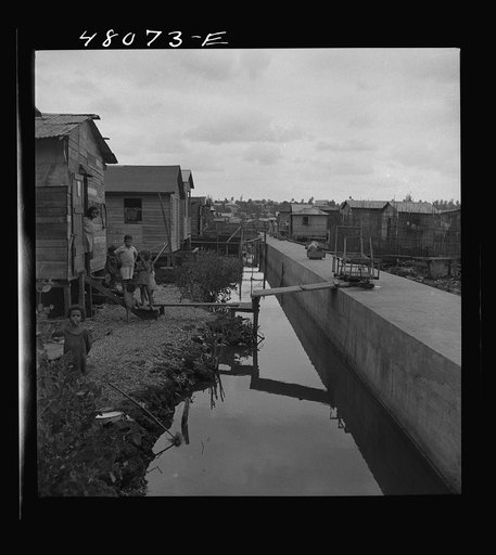 San Juan, Puerto Rico. In the huge slum area known as "El Fangitto." The concrete causeway is the sewer line from the Eleanor Roosevelt housing project in Rio Piedras