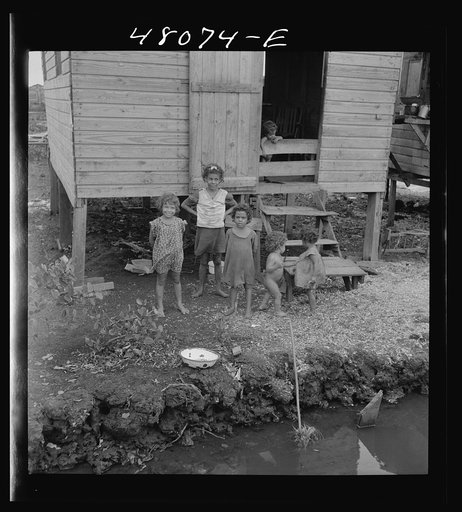 Untitled photo, possibly related to: San Juan, Puerto Rico. In the huge slum area known as "El Fangitto." The concrete causeway is the sewer line from the Eleanor Roosevelt housing project in Rio Piedras