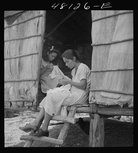 Utuado, Puerto Rico (vicinity). Stitching needlework at the home of a farm labor family in the hills. It is a widespread practice for factories to distribute hand work in this way