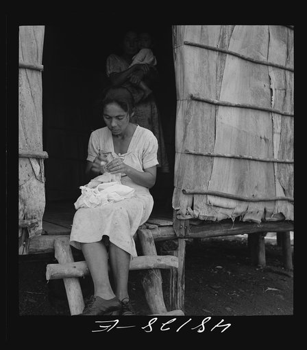 Utuado, Puerto Rico (vicinity). Stitching needlework at the home of a farm labor family in the hills. It is a widespread practice for factories to distribute hand work in this way