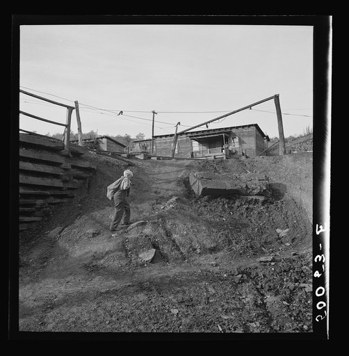 Untitled photo, possibly related to: Coal miner's son carrying home bag of coal swiped from cars. The "Patch," Chaplin, West Virginia. Note live wires. See 50054-E