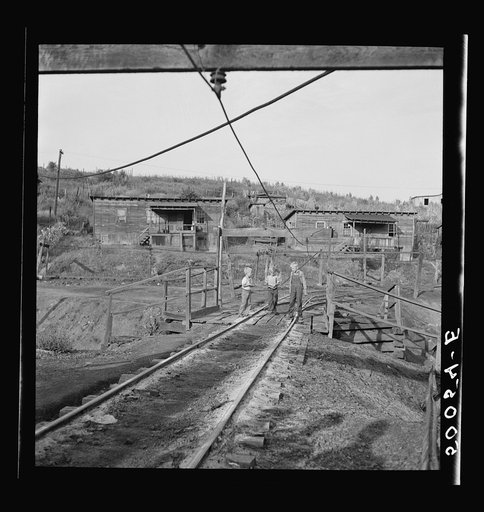 Coal miner's children on way to get groceries. All these wires are alive, carrying from 250 to 530 volts. People and children are often knocked down, sometimes killed. This is the main and only thoroughgare to company store and school, from their homes (in background). The "Patch," Chaplin, West Vir