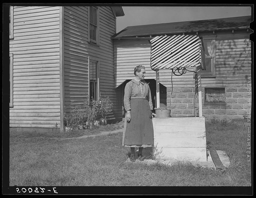 Farm woman standing by well. West Virginia