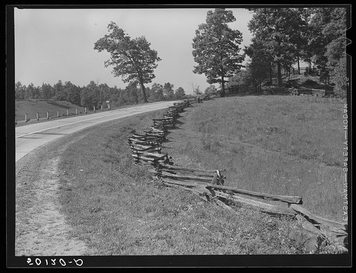 A new main highway with old rail (snake) fence at edge of field beside it. West Virginia
