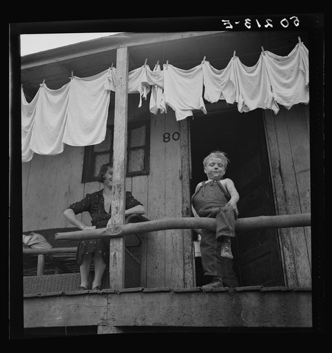 Untitled photo, possibly related to: Coal miner and son on porch of their home. The "Patch," Cassville, West Virginia