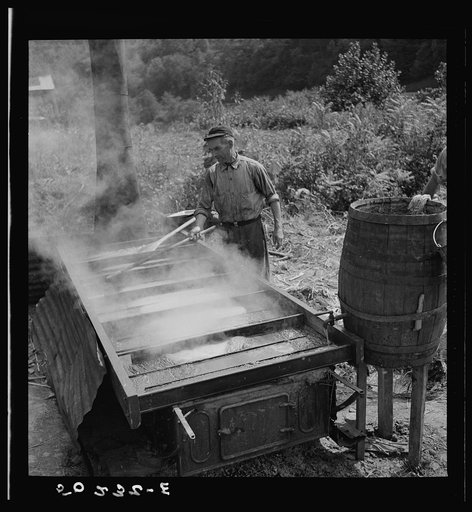 Sugarcane juice drains from barrel into vat, is boiled into molasses as it runs through to last section. Racine, West Virginia