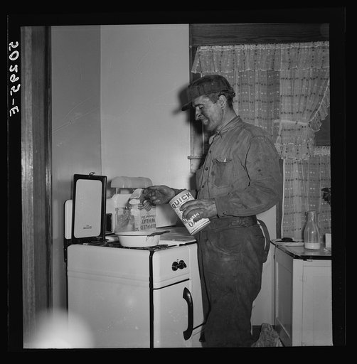 A more well-to-do miner starts his breakfast when he comes home in the morning after working on the night shift. He is Polish, his wife Hungarian. Westover, West Virginia