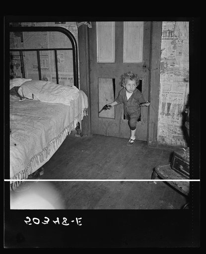 Why open the door, coal miner's child uses the "cat hole." Bertha Hill, West Virginia (Note pipe in one hand, gun in other)
