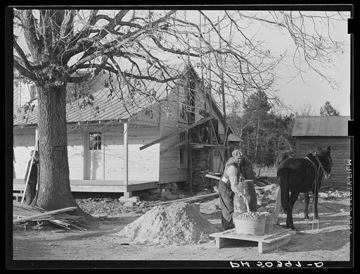 Negro rehabilitation client mixing cement to be used in construction of his new home near Raleigh, North Carolina