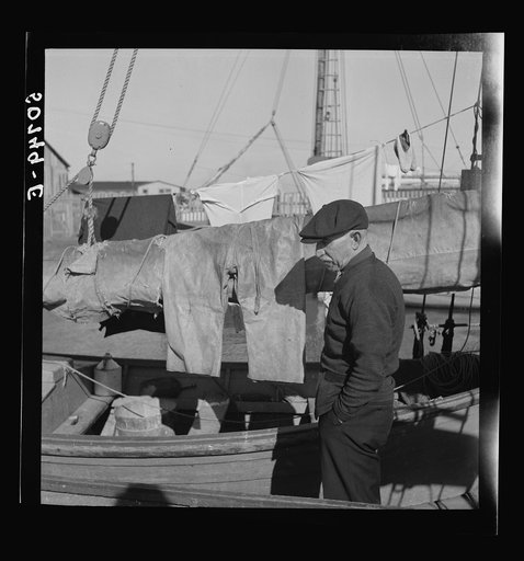 Fisherman oiling waterproof jackets and pants in boat. Christmas Day, Charleston, South Carolina