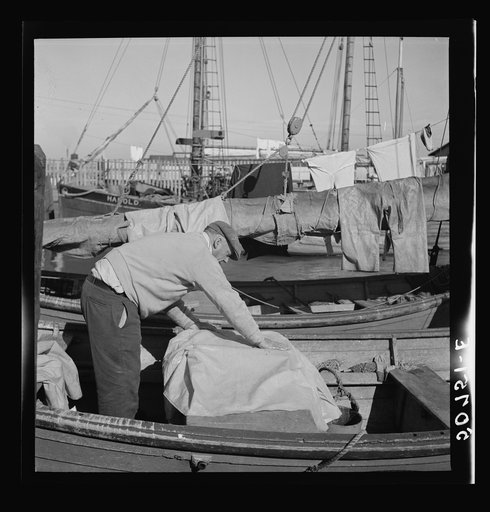 Fisherman oiling waterproof jackets and pants in boat. Christmas Day, Charleston, South Carolina