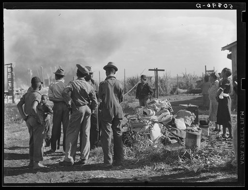 Untitled photo, possibly related to: Negro agricultural laborers watching one of their houses burn to the ground. All they have left is piled on the ground
