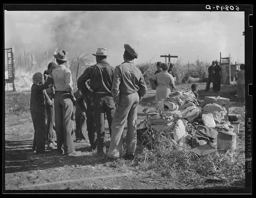 Negro agricultural laborers watching one of their houses burn to the ground. All they have left is piled on the ground
