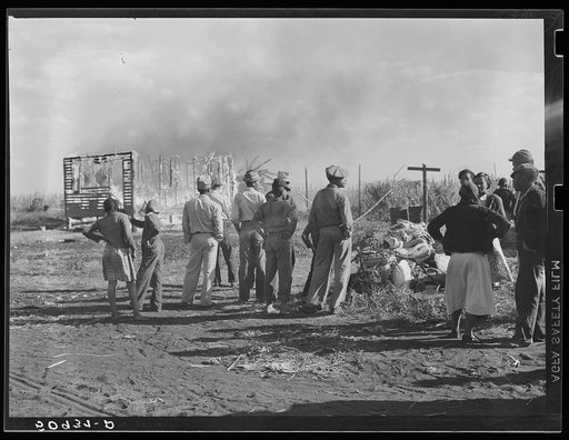 Negro agricultural laborers watching one of their houses burn to the ground. All they have left is piled on the ground. Lake Harbor, Florida