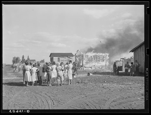 Negro agricultural laborers watching one of their houses burn to the ground. All they have left is piled on the ground. Lake Harbor, Florida