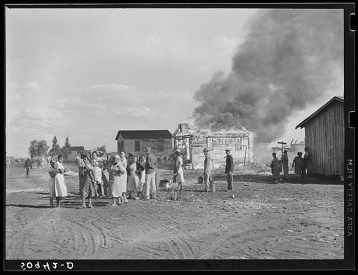 Untitled photo, possibly related to: Negro agricultural laborers watching one of their houses burn to the ground. All they have left is piled on the ground. Lake Harbor, Florida