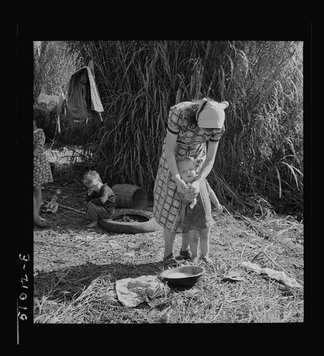 Untitled photo, possibly related to: Woman packinghouse worker from Tennessee trying to wash black muck, which causes an itchy rash and sores, off her youngest child. She has three others. The water came from a filthy canal nearby. Belle Glade, Florida