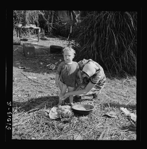 Untitled photo, possibly related to: Woman packinghouse worker from Tennessee trying to wash black muck, which causes an itchy rash and sores, off her youngest child. She has three others. The water came from a filthy canal nearby. Belle Glade, Florida