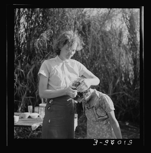 Untitled photo, possibly related to: Young woman packinghouse worker from Tennessee, trying to get the black muck, which causes an itchy rash and sores and scabs on scalp, out of her oldest child's hair. The water is from the dirty canal nearby. She has three other children. Belle Glade, Florida