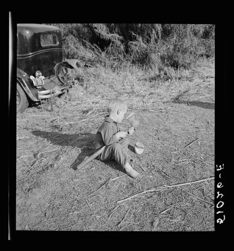 Playtime in front of migratory packinghouse worker's camp. Child is from Tennessee and his parents are away most of the time. Belle Glade, Florida