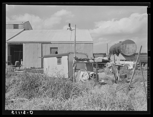 Migrant vegetables and packinghouse workers. "The scramble for that rare and valuable commodity--work." The trailer is next to the packinghouse door so that its occupants may by the first on call when work is available, Belle Glade, Florida