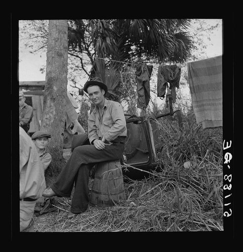 Migrant laborer, Canal Point, Florida. He is sitting on a bean hamper, which they call "muck-rockers."