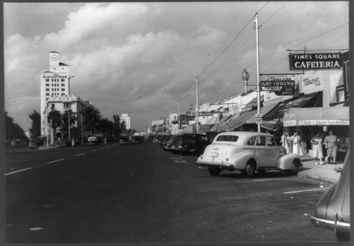 One of Miami's streets showing varied small shops, signs, and tourist bureaus. Miami Beach, Florida