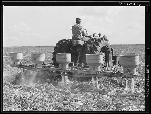 Fertilizer for large fields of sugarcane distributed by tractor-driven fertilizer machine. USSC (United States Sugar Corporation). Clewiston, Florida
