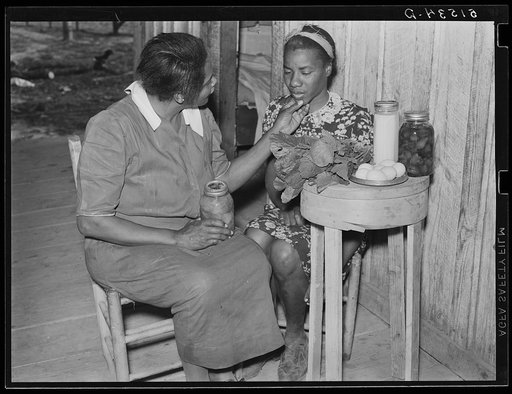 Untitled photo, possibly related to: Nurse Shamburg gives Viola Pettway instructions and help about her diet in treatment of pellagra. She has been sick about four years and is a little better now. Her mother has thirteen children and twenty-five dollars a month for all. Table top is made from chees