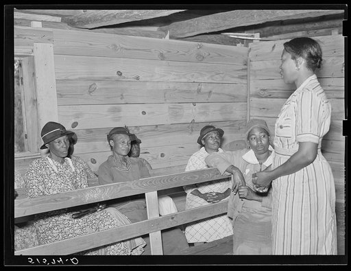 Juanita Coleman, NYA (National Youth Administration) leader and teacher, talking to adult class, held in old church building. They are learning reading, writing, arithmetic, and have general discussion and educational activities. Gee's Bend, Alabama