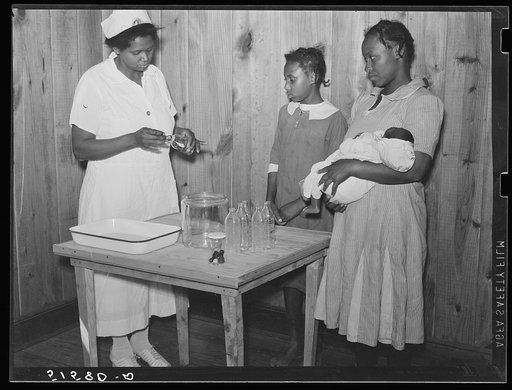 Nurse Shamburg demonstrates care of baby bottles to Mrs. Paralee Coleman and Marie. Mothers have to work in field and children are left at home to care for babies. Health clinic, Gee's Bend, Alabama