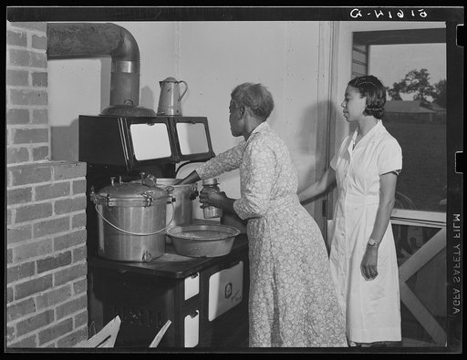 Ada Turner and Evelyn M. Driver home management and home economics supervisor, canning English peas with pressure cooker in Mrs. Missouri Thomas' kitchen. Flint River Farms, Georgia