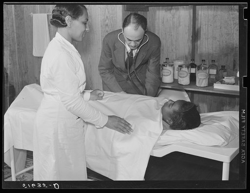 Project nurse Lillie Mae McCormick assists Dr. Thomas M. Adams as he takes Annie Maude Daniels' blood pressure on table in health clinic. Flint River Farms, Georgia