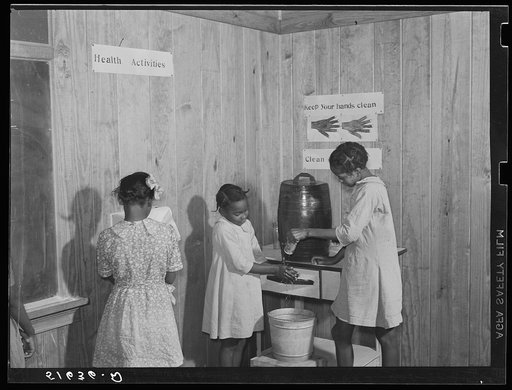 Gladys Crimer drying her hands on paper towel and Bernice Mathis and Edna Law washing theirs in clean-up corner in second and third grade school room. Flint River Farms, Georgia
