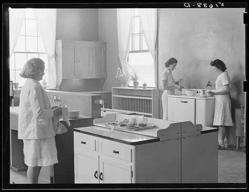 Margaret Segars at sink with dinner tray showing well-balanced meal at right. In background are Dorothy Smith and Elizabeth Atkinson cooking on electric stove in home economics class room in school building. Ashwood Plantations, South Carolina