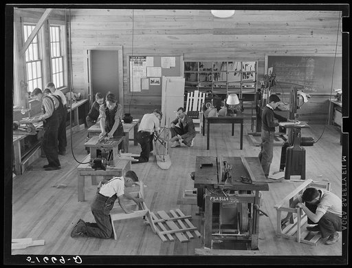 Part of shop class in school with Robert Gentry, teacher, in center kneeling next to boy who is making ironing board. Ashwood Plantations, South Carolina