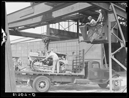 Hooking shepard crane to tractor preparatory to hoisting it off truck to repairs shop in FSA (Farm Security Administration) warehouse depot. Atlanta, Georgia