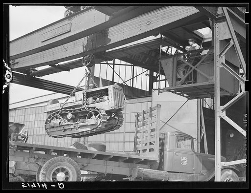 Tractor, transported by truck to FSA (Farm Security Administration) warehouse depot for repairs, being hoisted by Shepard crane to shop inside. Atlanta, Georgia