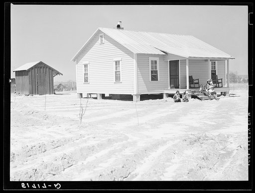 New home and smokehouse of Charles McGuire (tenant purchase borrower) with his wife and children on front porch. Pike County, Alabama
