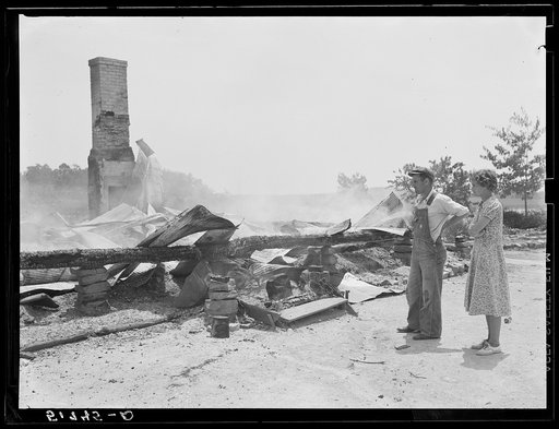 Tenant farmer and wife looking at ruins of home burned to ground. Greene County, Georgia