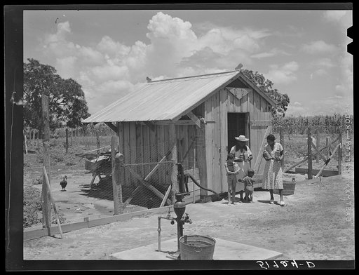 Wife of Frederick Oliver, tenant purchase client, bringing canned goods from smokehouse. Note driven well. Summerton, South Carolina