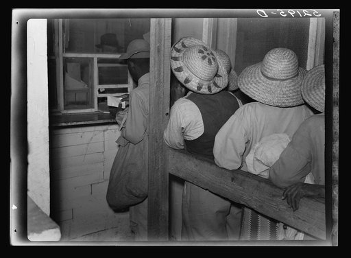 Negro day laborers brought in truck from nearby towns, waiting to be paid off for cotton picking and buy supplies inside plantation store on Friday night. Marcella Plantation. Mississippi Delta. Mississippi