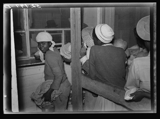 Negro day laborers brought in truck from nearby towns, waiting to be paid off for cotton picking and buy supplies inside plantation store on Friday night. Marcella Plantation. Mississippi Delta. Mississippi