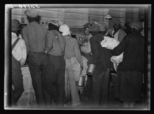 Negro day laborers brought in truck from nearby towns, waiting to be paid off for cotton picking and buy supplies inside plantation store on Friday night. Marcella Plantation. Mississippi Delta. Mississippi