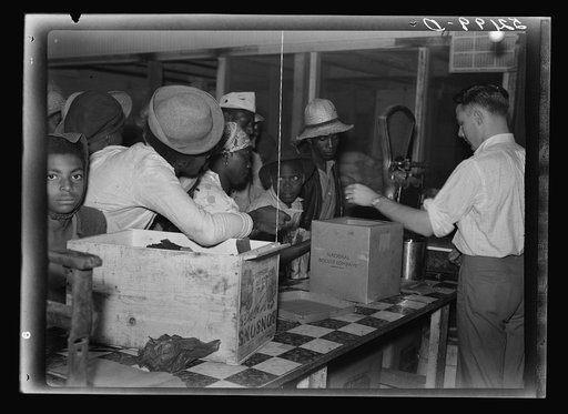 Negro day laborers brought in truck from nearby towns, waiting to be paid off for cotton picking and buy supplies inside plantation store on Friday night. Marcella Plantation. Mississippi Delta. Mississippi